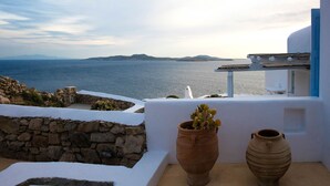 Une terrasse avec vue sur la mer, un mur en pierre et deux pots de fleurs.