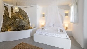 Une chambre à coucher avec un lit, un grand mur en pierre et deux lampes de chevet.