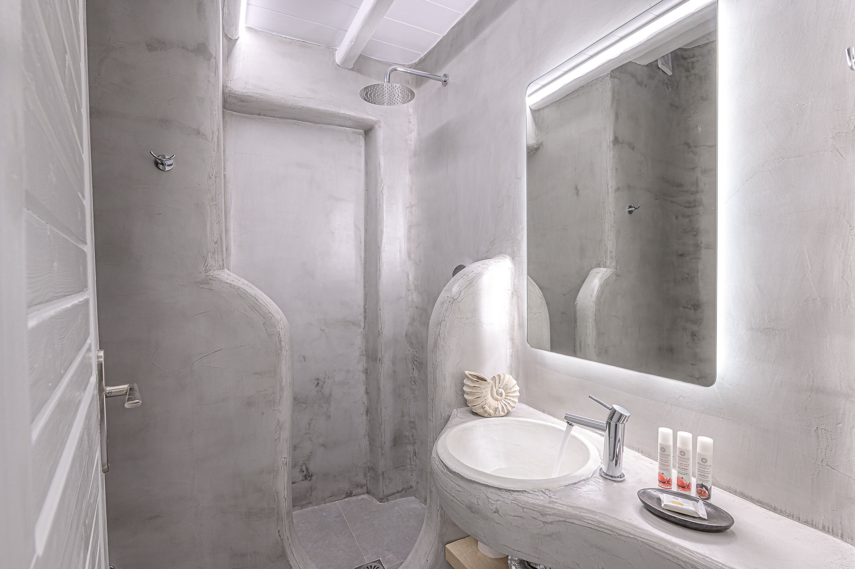 A bathroom with a large mirror, a sink, and a shower.