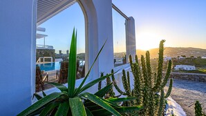 Un bâtiment blanc doté d’une piscine et de chaises, offrant une vue sur un paysage parsemé de cactus et sous un ciel dégagé.
