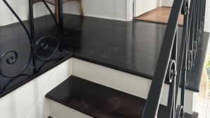 Eine Treppe mit schwarzen Metallgeländern, einer Korbsitzbank und einem Feuerlöscher an der Wand.