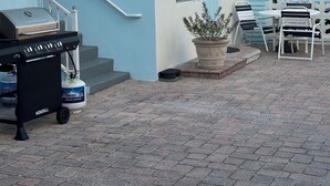 Eine Terrasse mit Grill, Sitzgelegenheit und einem Blumentopf.
