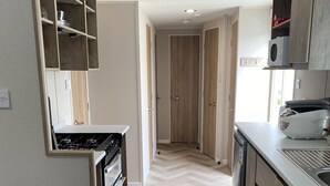 Una cucina moderna con elettrodomestici integrati, un pavimento a spina di pesce e un corridoio che conduce a una porta.