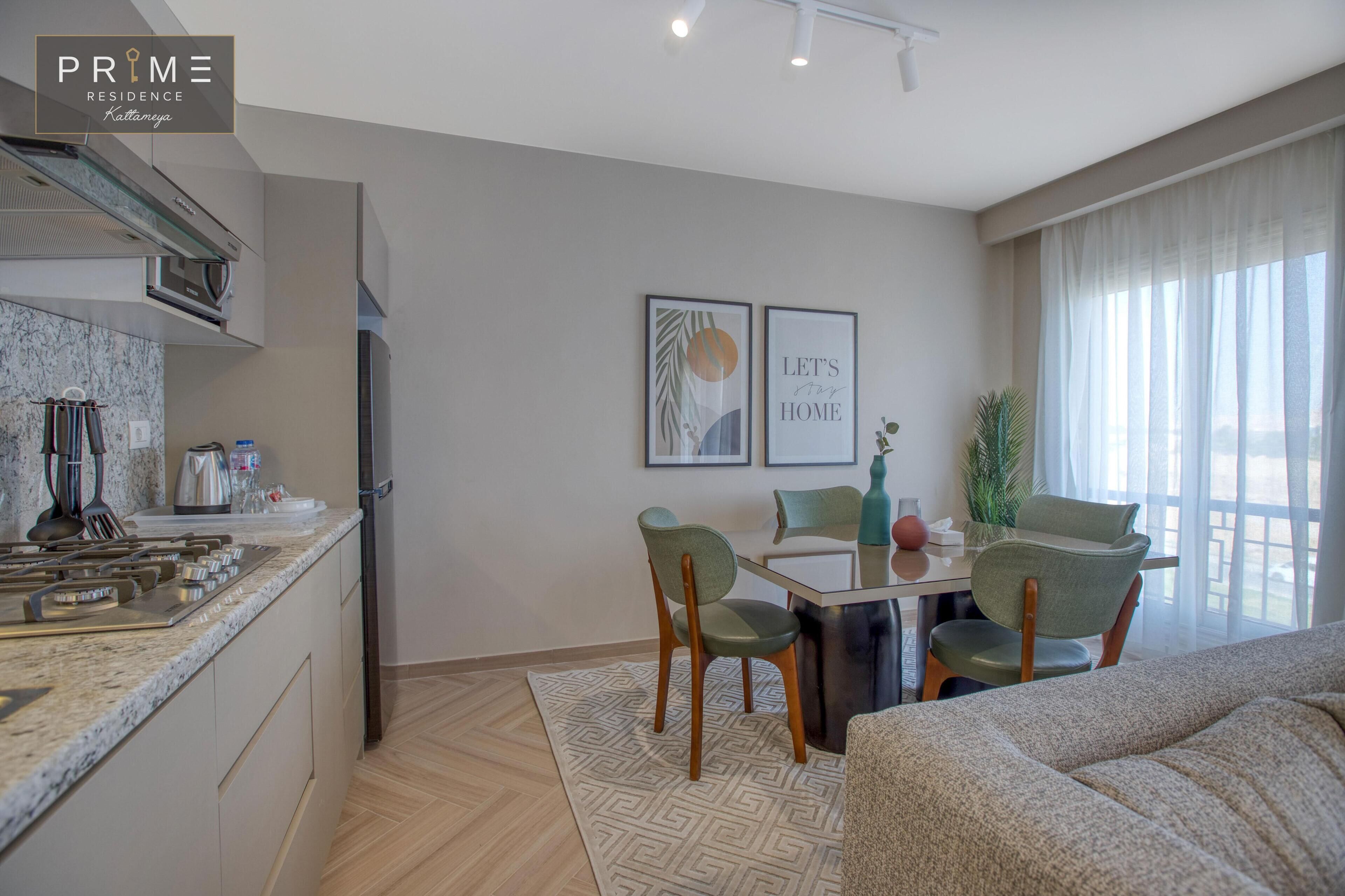 A modern kitchen with a built-in stove, a dining area with a table and chairs, and a living area with a sofa.