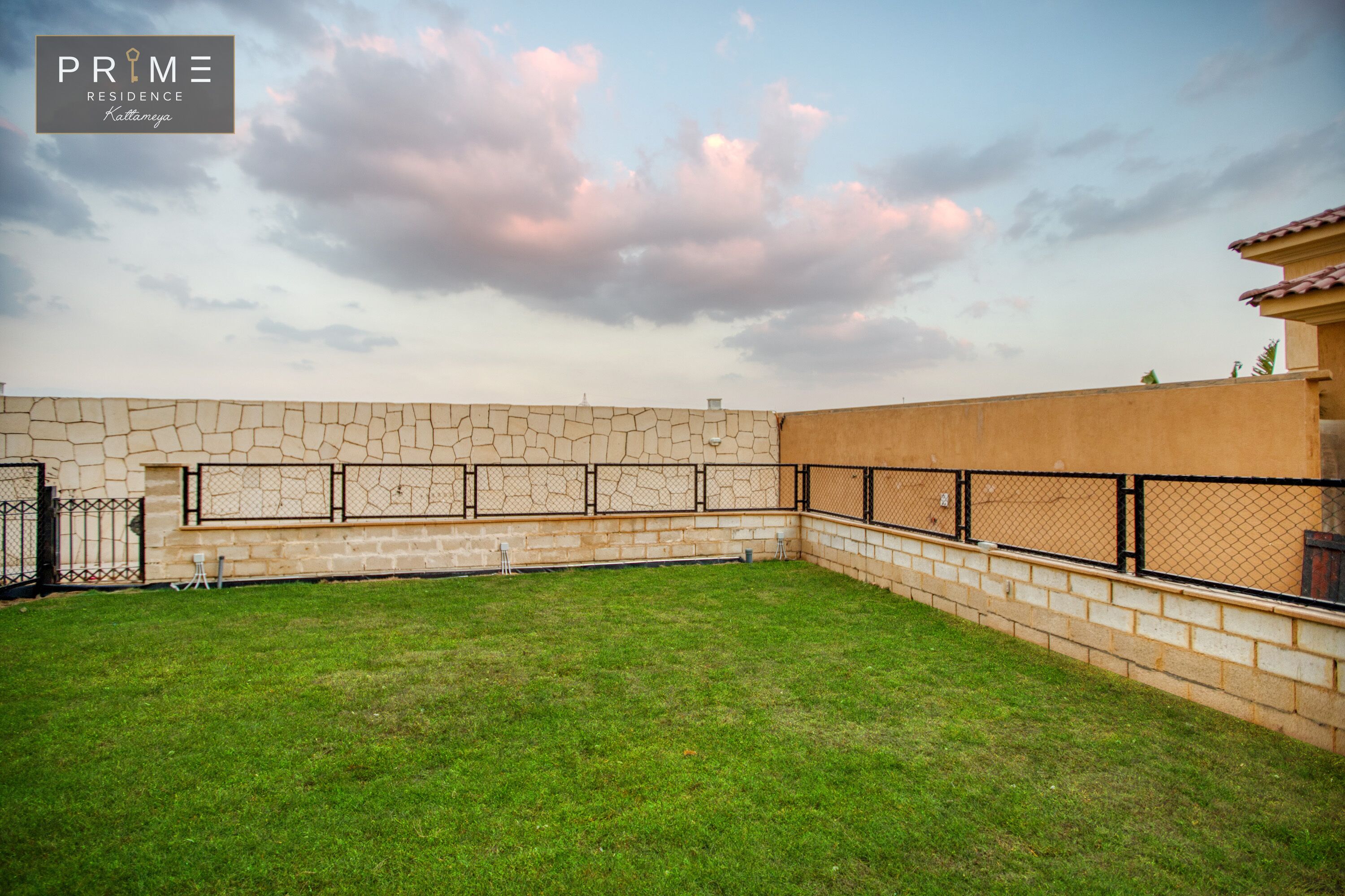 A spacious outdoor area with a stone wall and a fenced patio.