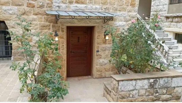 A stone building with a wooden door, a metal gate, and a staircase.