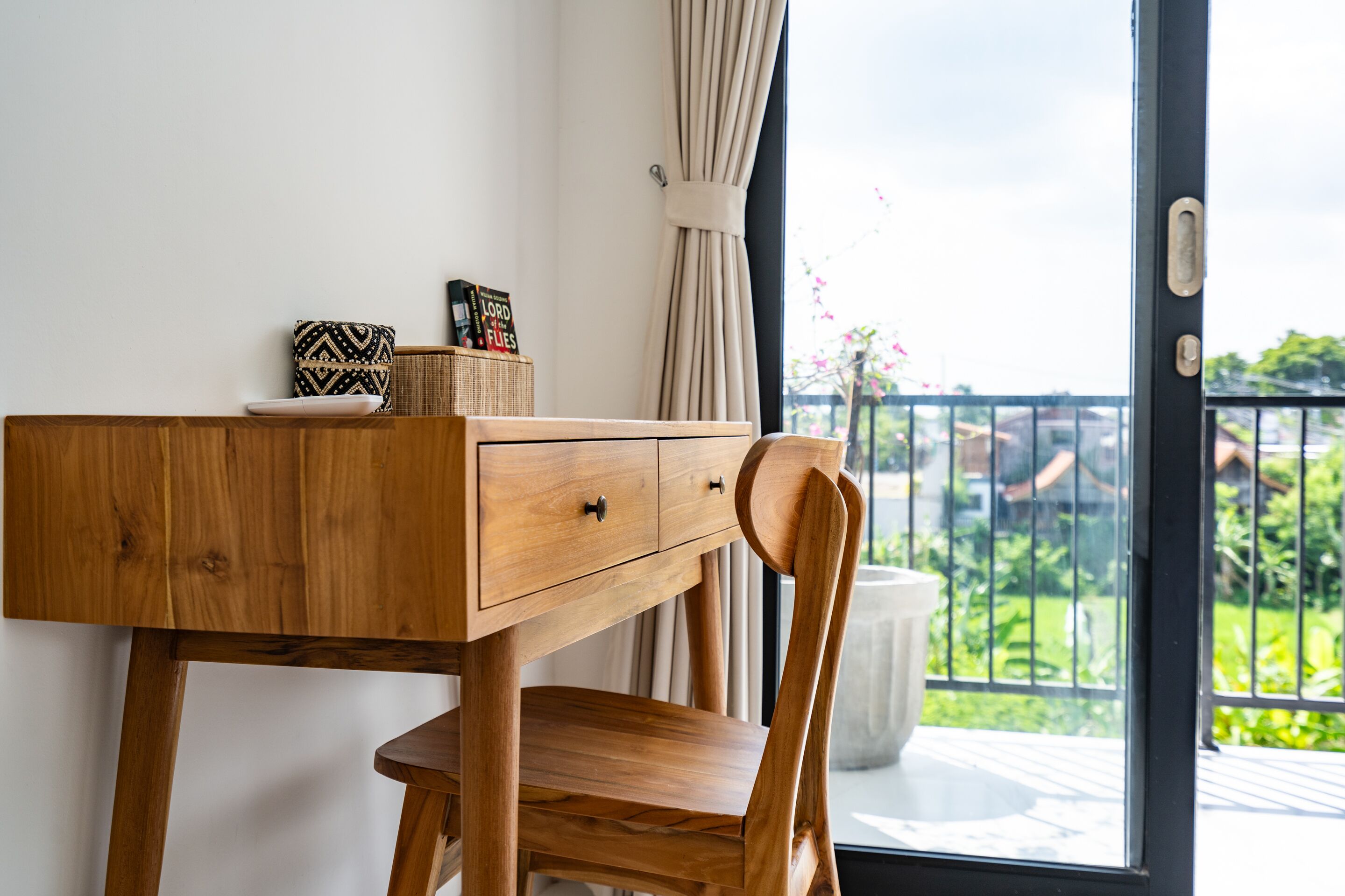 Un escritorio de madera con una silla, una cesta pequeña y un libro titulado 