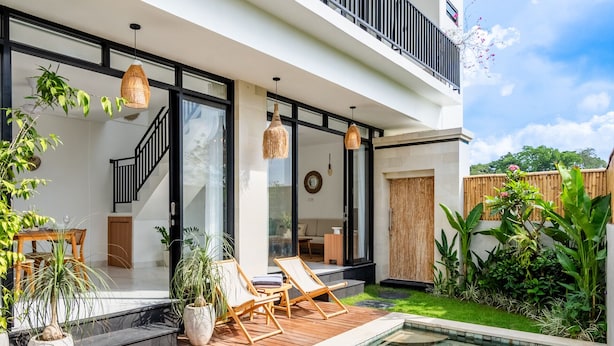Una casa moderna con piscina, terrazza in legno e area salotto esterna.