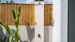 Un edificio moderno con un recinto in bambù e un elemento decorativo a base d'acqua.