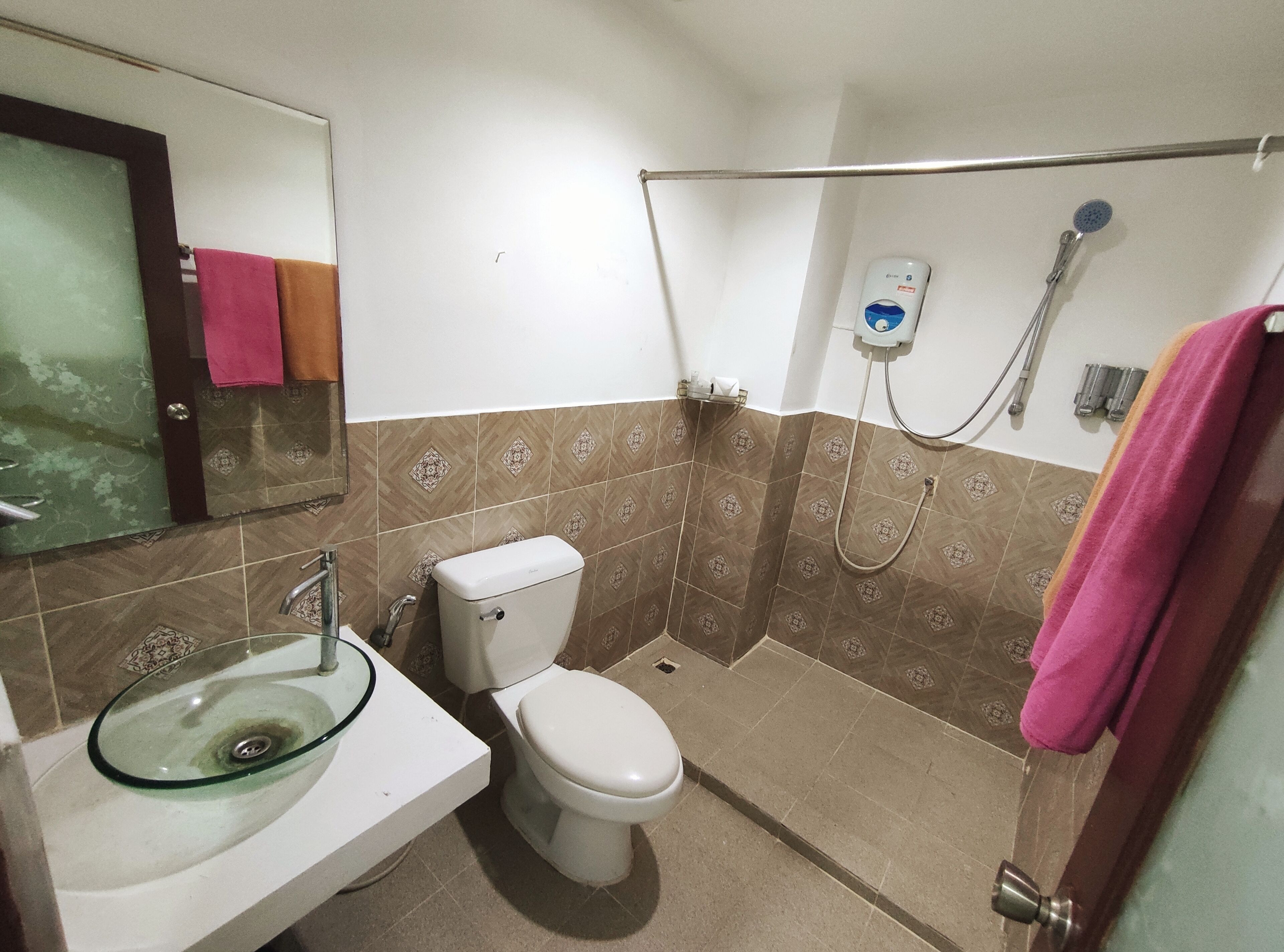 A bathroom with a toilet, a glass sink, and a shower.