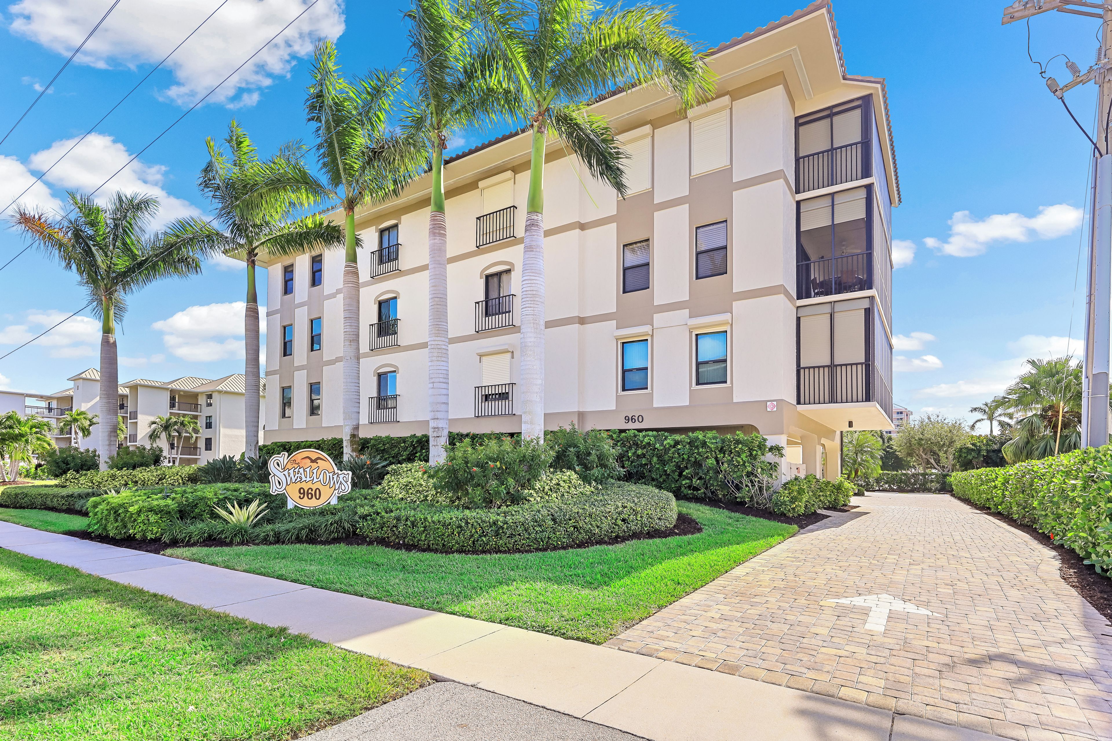 A multi-story residential building with a paved driveway and landscaped garden.