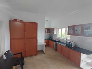 A kitchen with wooden cabinets, a black countertop, and a microwave.