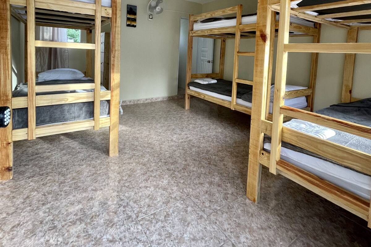 A room with bunk beds, a ceiling fan, and a tiled floor.