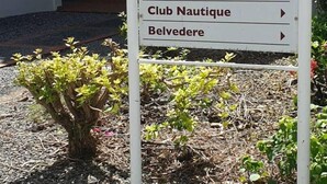 A sign listing various amenities including a boutique, lavoir, club for children, air de jeux, beach volley, club plongée, club nautique, and belvedere. - Studio Tropical Avec vue sur le Rocher du Diamant (Sainte-Luce)