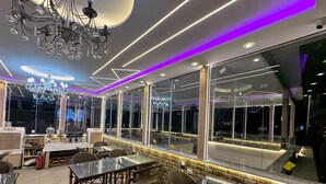 A modern restaurant interior with glass tables, cushioned chairs, and a chandelier. - Nun Pyramids INN (Giza)