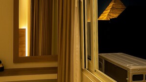 A room with a large window, a door with curtains, and a small table. - Nun Pyramids INN (Giza)