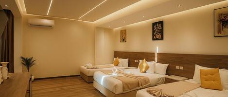 A hotel room with two beds, a wooden dresser, a small table, and a wall-mounted air conditioner.