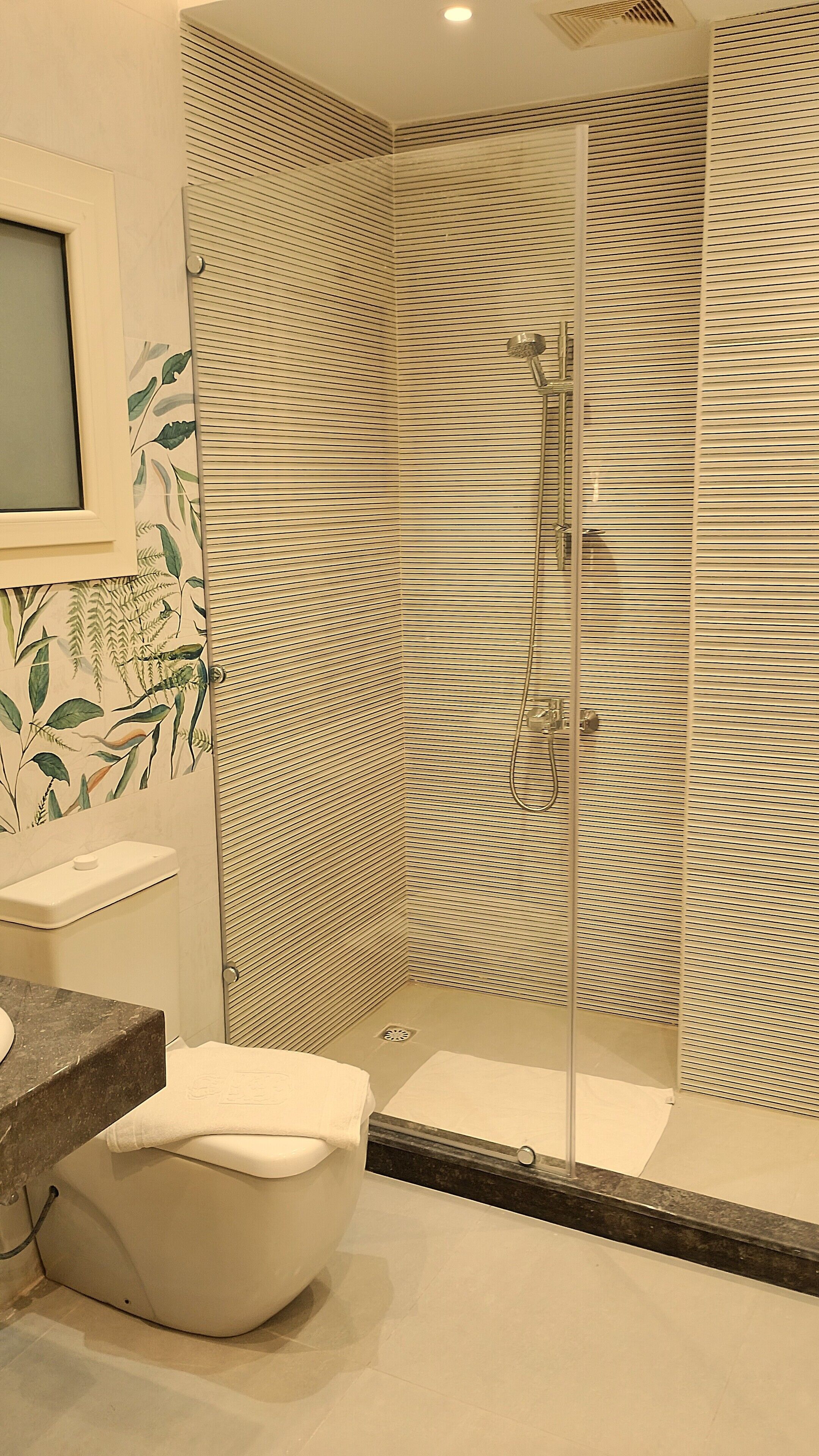 A modern bathroom with a shower, toilet, and sink.