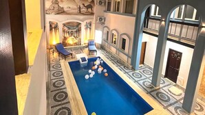 A pool area with lounge chairs and a decorative wall. - Nun Pyramids INN (Giza)