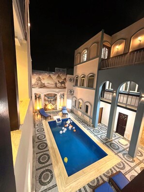 Una piscina al aire libre, sombrillas, sillones reclinables de piscina