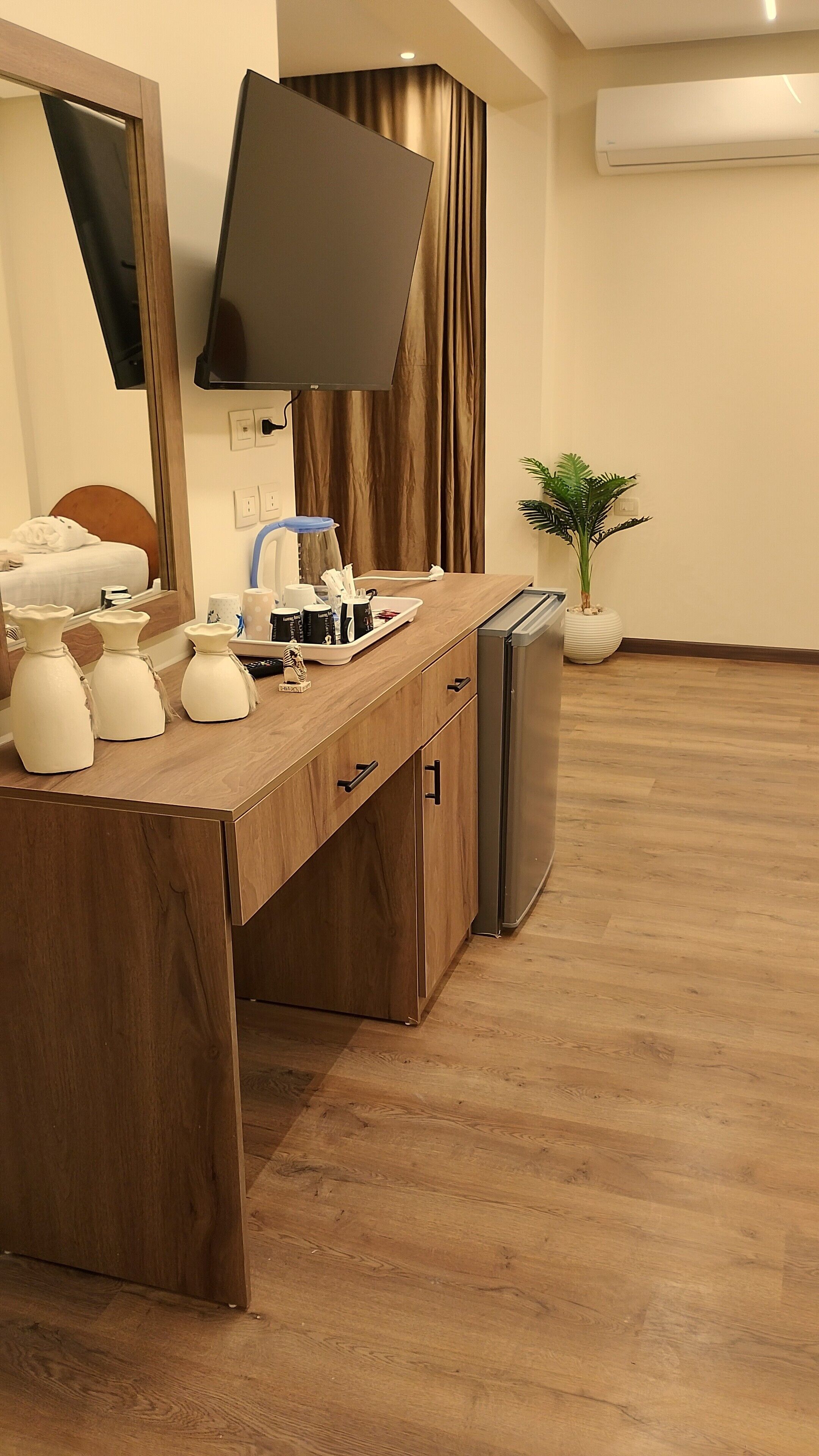A modern kitchen with a wooden countertop, a built-in refrigerator, a flat-screen TV mounted on the wall, and a potted plant.