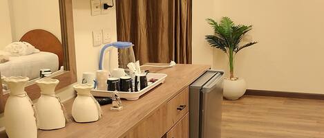 A modern kitchen with a wooden countertop, a built-in refrigerator, a flat-screen TV mounted on the wall, and a potted plant.