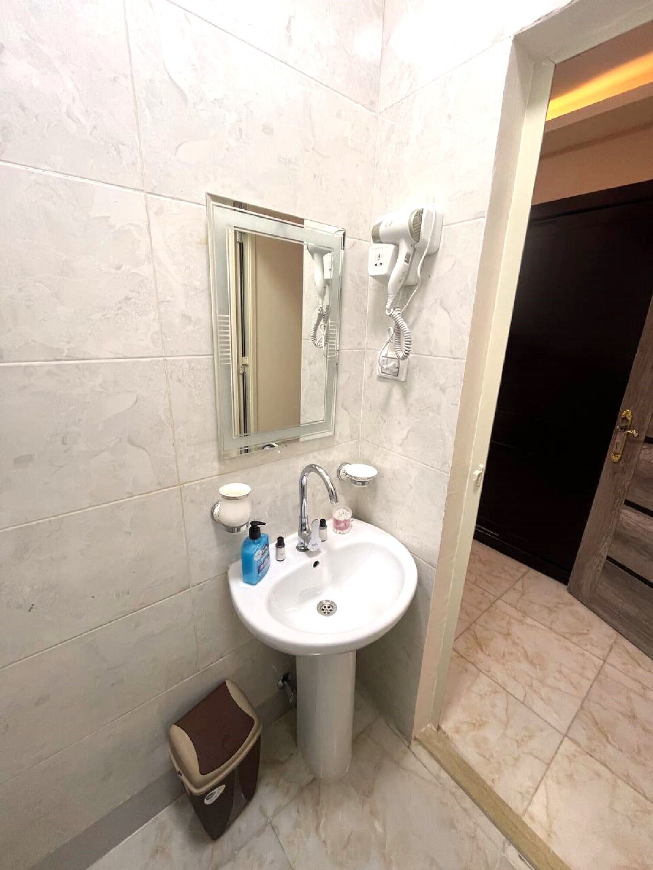 A bathroom with a white sink, a mirror, and two hair dryers mounted on the wall.