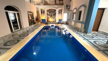 Una piscina al aire libre, sombrillas, sillones reclinables de piscina