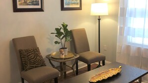 A living room with two chairs, a table, a lamp, and two framed paintings on the wall. - Historic Home Steps from Florida Southern, Lake Morton and Lake Hollingsworth (Lakeland)