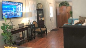 A living room with a television, wooden furniture, a ceiling fan, and a dining area. - Historic Home Steps from Florida Southern, Lake Morton and Lake Hollingsworth (Lakeland)