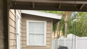 A porch with a swing seat, a small window, and a covered grill area. - Historic Home Steps from Florida Southern, Lake Morton and Lake Hollingsworth (Lakeland)