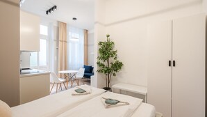 Una habitación de hotel moderna con dos camas, una zona de comedor y una kitchenette.