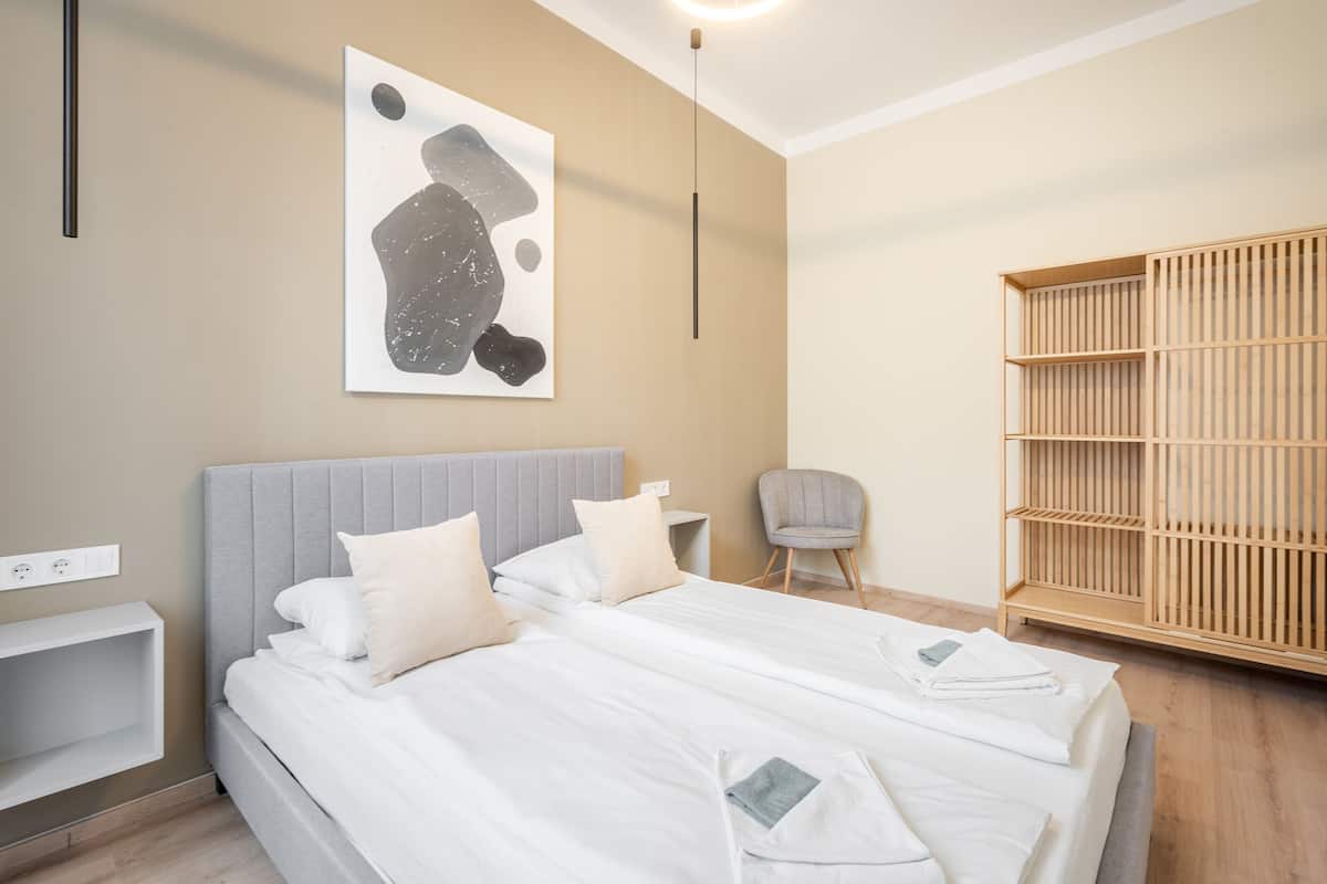 Ein modernes Hotelzimmer mit einem großen Bett, einem Nachttisch, einem Sessel und einem Kleiderschrank.