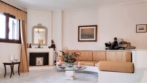 A living room with a fireplace, a sofa, a coffee table with flowers, and a painting on the wall. - Christie's Boutique by Corfuescapes  (Corfu)