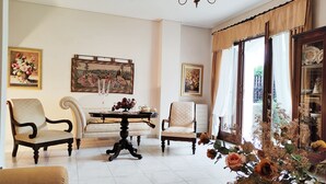 A room with a dining table, two armchairs, a sofa, and a chandelier. - Christie's Boutique by Corfuescapes  (Corfu)