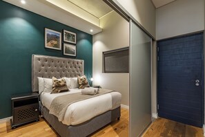 Una camera da letto con un letto grande, un comodino, una porta scura e quadri appesi al muro.
