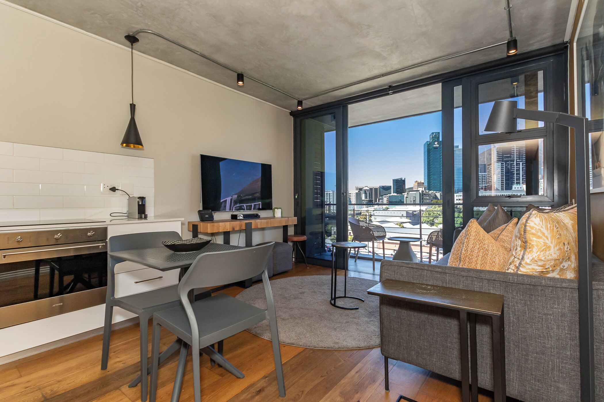Une cuisine moderne avec un coin repas, un téléviseur à écran plat et une vue sur la ville grâce à de grandes fenêtres.