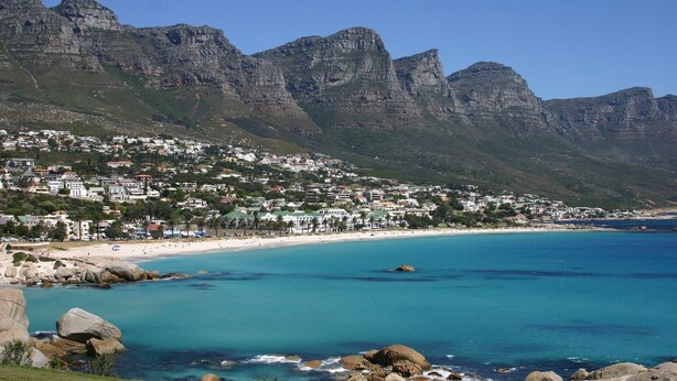 A coastal town with a beach, rocky coastline, and mountains in the background. - Docklands Deluxe Apartments by ITC Hospitality (Cape Town)