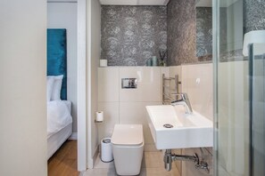 Un bagno moderno con lavandino bianco, un water e una zona doccia.