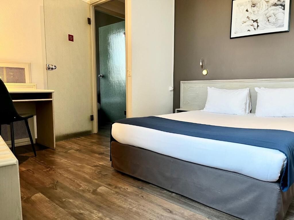 A hotel room with a bed, a desk, and a chair.