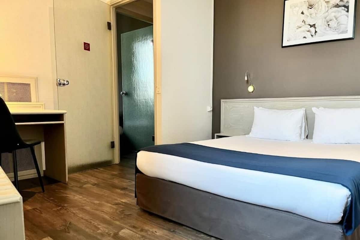 A hotel room with a bed, a desk, and a chair.