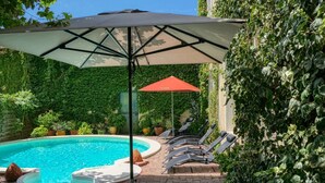 Un espace piscine équipé d’un jacuzzi, de chaises longues et de parasols.