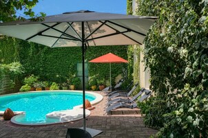 Una piscina al aire libre de temporada, sombrillas