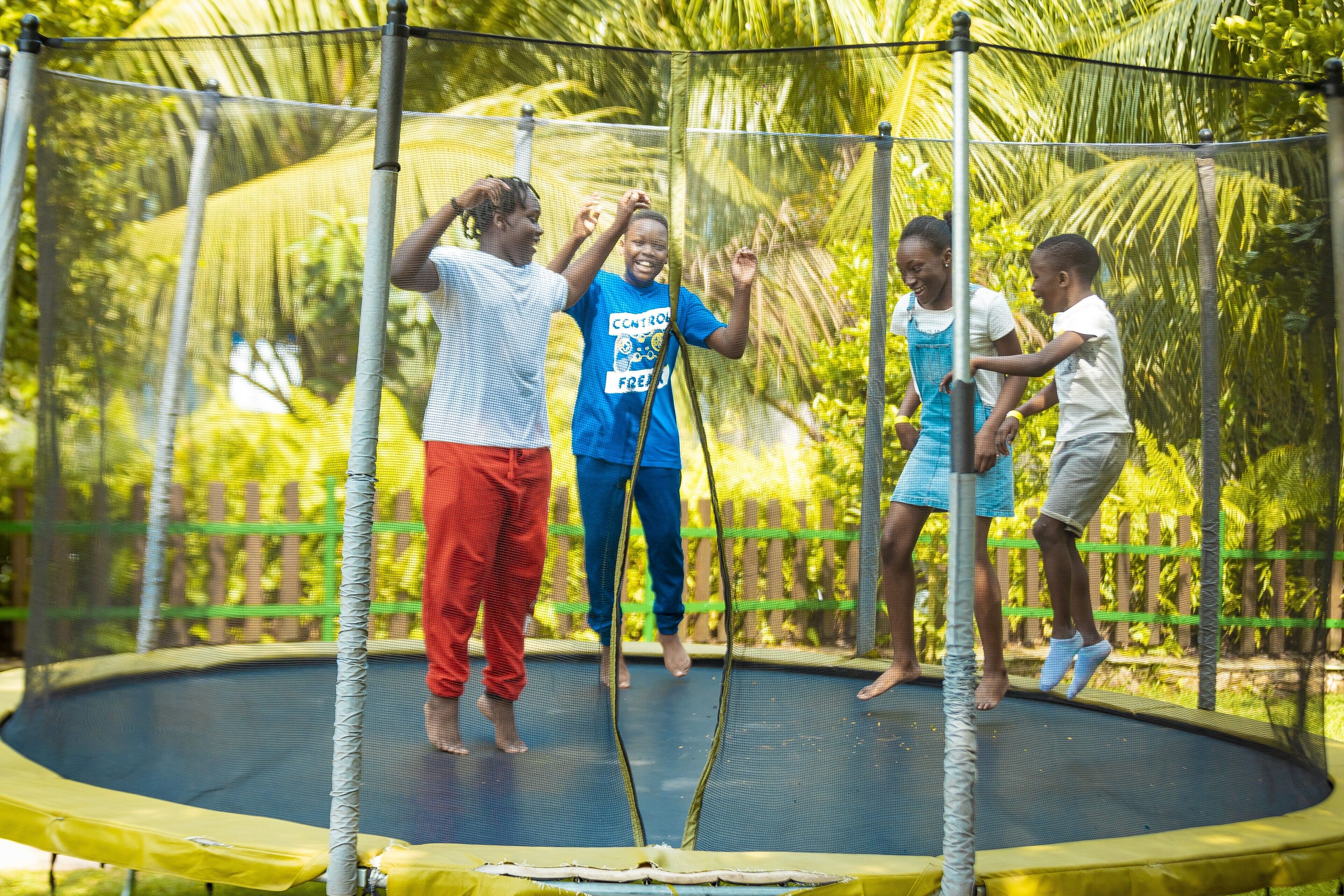 A trampoline surrounded by a safety net, with people jumping.