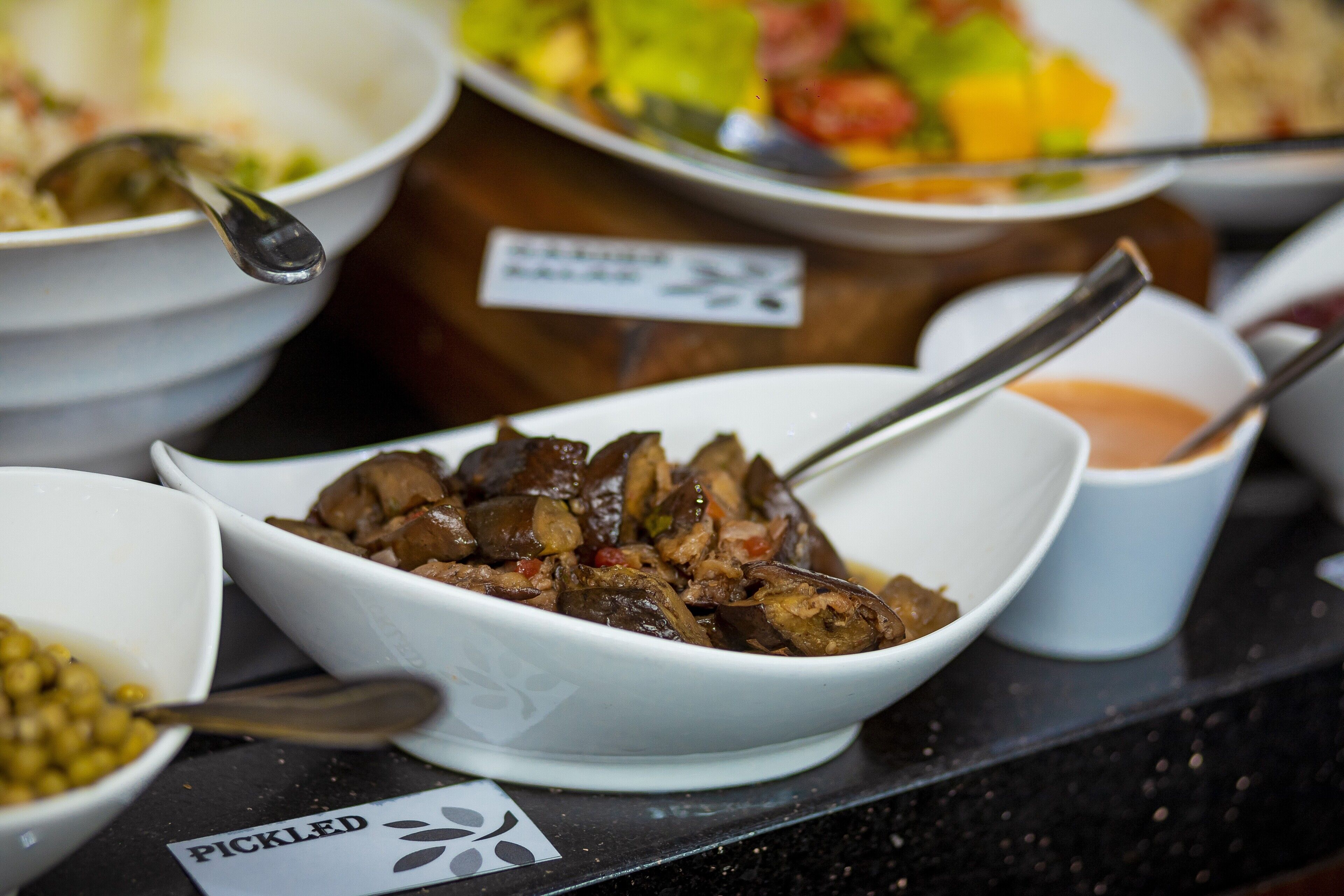 A variety of dishes on a table, including a bowl of pickled vegetables, a bowl of meat, and a cup of sauce.
