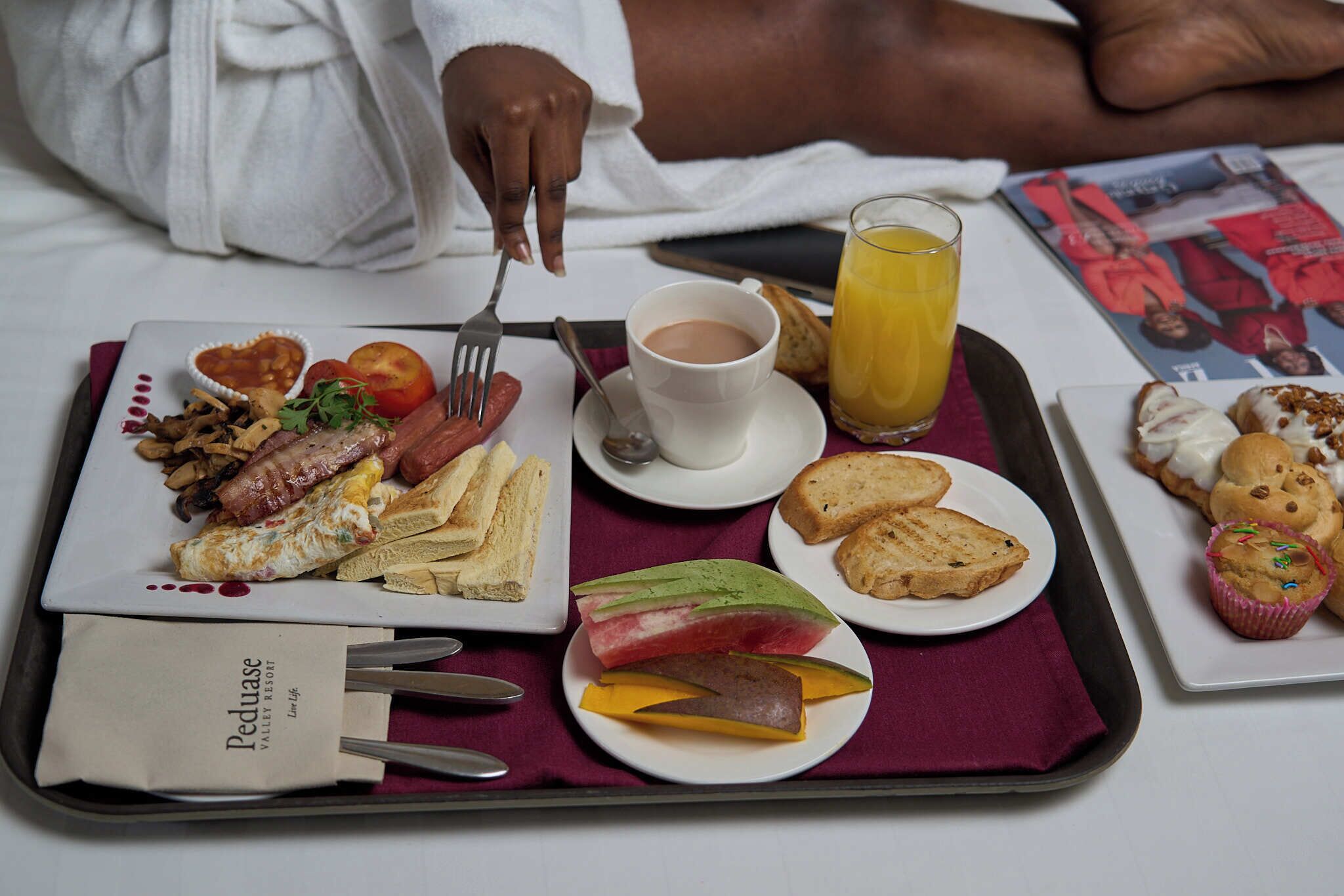 A breakfast tray with toast, eggs, tomatoes, and a cup of coffee.