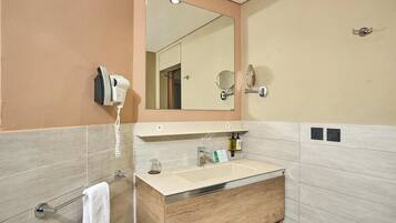 A modern bathroom with a beige vanity, a large mirror, a hairdryer, and a towel rack.