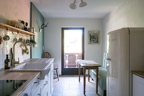 Una cocina con encimera de madera, un fregadero, una mesa de comedor y un refrigerador.