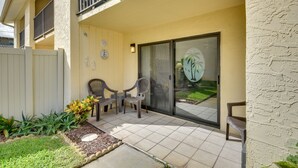 A patio area with a sliding glass door, outdoor chairs, and a small garden with plants. - Daytona Beach Shores Condo Rental: Walk to Beach! (Daytona Beach Shores)