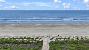 Une plage avec une promenade en bois menant à l’eau, une plage de sable et un ciel dégagé.